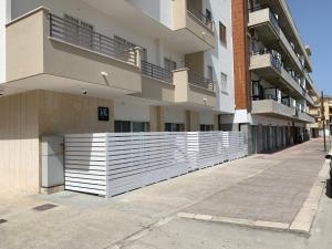a white fence in front of a building at Bianco&Nero 141 Apartament in Margherita di Savoia
