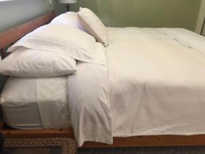 Cama blanca con sábanas y almohadas blancas en The Great Kona Escape en Kailua-Kona