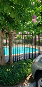 a fence with trees in front of a swimming pool at Cozy Condo in Houston