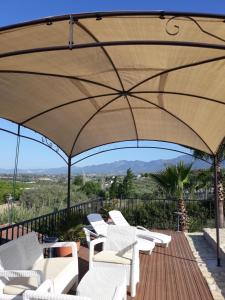 un patio con sillas blancas y una sombrilla grande en Villafranco Apartamentos en Villafranco de Guadalhorce