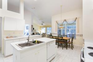 a white kitchen with a sink and a table at Serene & Attractive Heated Pool Spa Home in Estero