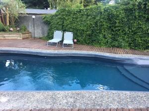 Duas cadeiras sentadas num deque ao lado de uma piscina em Hotel Casa Marron em Villarrica