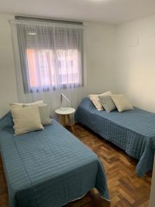 een kamer met 2 bedden, een tafel en een raam bij Departamento Nueva Cordoba pa 4personas in Cordoba