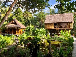 a house in a garden with a pond in front of it at Jasri Dalem Surf Retreat in Jasri