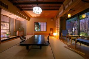 uma sala de estar com uma mesa, cadeiras e janelas em Oyado Ichizen em Yufu
