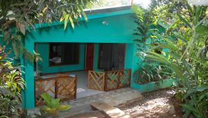 a blue house with a porch in a forest at CasitaCecropia Rental in Drake