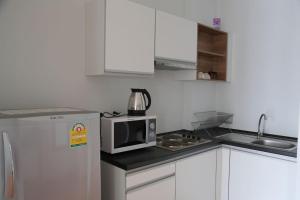 a kitchen with a microwave and a refrigerator at At Sea Condo in Klong Muang Beach