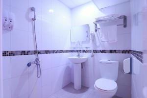 ein weißes Bad mit einem WC und einem Waschbecken in der Unterkunft E Lim Hotel in Zhongli