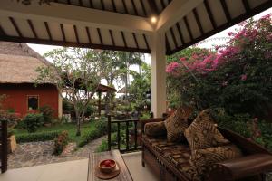 a screened in porch with a couch and a garden at Puri Mas Boutique Resort & Spa in Senggigi