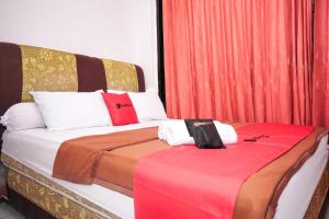 1 dormitorio con 2 camas y cortinas rojas en RedDoorz near Palembang Square Mall 2, en Palembang