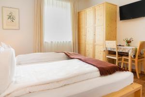een slaapkamer met een bed, een tafel en een raam bij Gästehaus Seitzhof in Merano