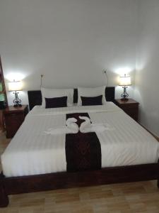 a bedroom with a large white bed with two lamps at Caga Garden in Nusa Penida