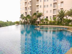 a large swimming pool in front of a building at Comfy Studio Apartment No Kitchen Mustika Golf Residence By Travelio in Pegadungan
