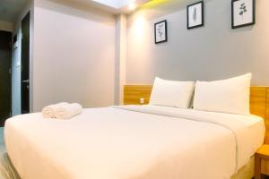 a bedroom with a large white bed with two rolled towels at Comfy Studio Apartment No Kitchen Mustika Golf Residence By Travelio in Pegadungan +6 photos