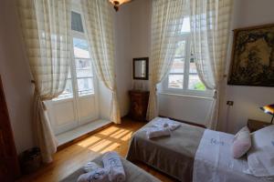 a bedroom with two beds and two windows at Hydra's Pearl - Gold Pearl in Hydra
