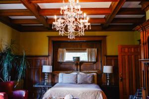 Dashwood Manor Seaside Bed & Breakfast في فيكتوريا: غرفة نوم بسرير وثريا