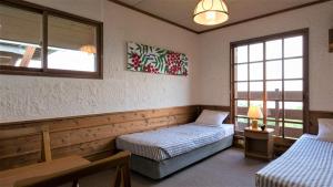 a bedroom with two beds and a window at Blueberry Pension Madarao in Iiyama