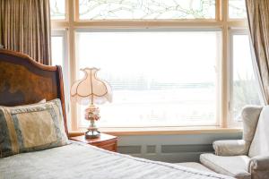 Dashwood Manor Seaside Bed & Breakfast في فيكتوريا: غرفة نوم بسرير وكرسي ونافذة