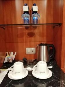 a tea kettle and two cups on a counter at Jupiter International Hotel - Bole in Addis Ababa