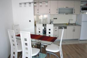 a kitchen with a table and white chairs and a counter at Lucija Apartments in Krk +30 photos
