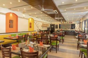 une salle à manger avec des tables et des chaises dans un restaurant dans l'établissement Kyriad Prestige Calangute Goa by OTHPL, à Calangute