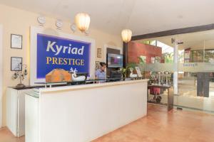 Una donna in piedi al bancone di un negozio di prestigio Kyrid. di Kyriad Prestige Calangute Goa by OTHPL a Calangute