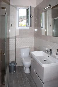 a bathroom with a toilet and a sink at SUNSHINE APARTMENT CITY CENTER in Karpathos +37 photos