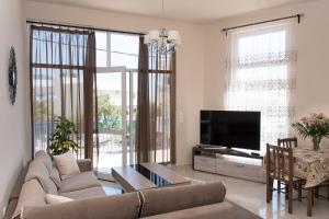 a living room with a couch and a tv at SUNSHINE APARTMENT CITY CENTER in Karpathos