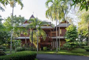 una casa in legno con palme di fronte di Phowadol Resort And Spa a Chiang Rai