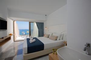 1 dormitorio con cama, bañera y TV en Archipelagos Hotel en Rethymno