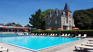 uma piscina com espreguiçadeiras e um edifício em Hotel Ker Juliette em Pornichet