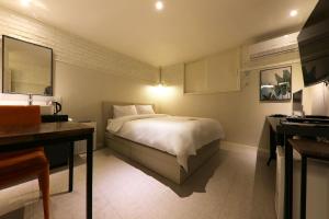 大田的住宿－Hotel Yam，一间卧室配有一张床、一张桌子和一张四柱床。