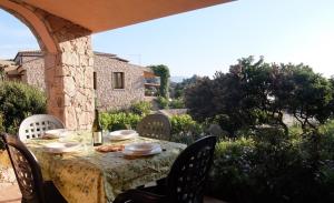 a table with chairs and a table with a bottle of wine at Villino Saccu in Costa Paradiso