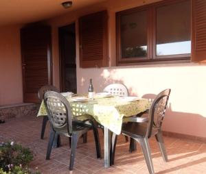 a table with chairs and a bottle of wine on it at Villino Saccu in Costa Paradiso