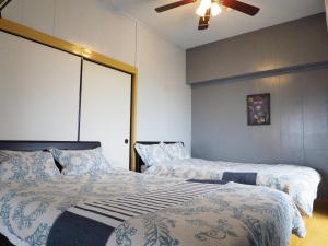 a bedroom with two beds and a ceiling fan at Holiday Homes TSUBOYA 505 in Naha