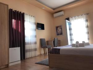 a bedroom with a bed and a tv and windows at Hotel Floga in Shkodër