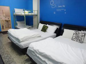 Cette chambre comprend 2 lits avec des draps et des oreillers blancs. dans l'établissement Kite Hostel, à Chiayi