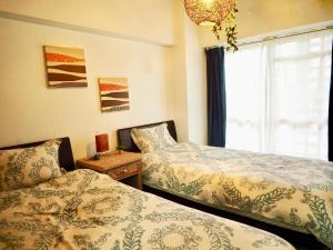 um quarto com 2 camas e uma janela em Holiday Homes TSUBOYA 301 em Naha
