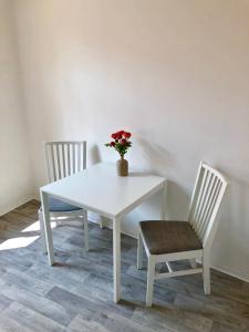 a white table with two chairs and a vase with flowers at Apartmán Pisek centrum in Písek