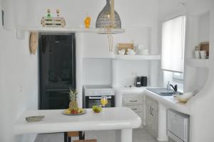 una cocina blanca con una bandeja de fruta en una mesa en Villa kleio Naxian album with private pool en Glinado Naxos