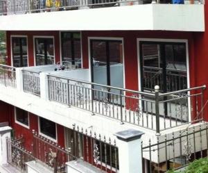 碧瑤的住宿－雅瓦萊斯登西公寓，一座红色的建筑,旁边设有阳台