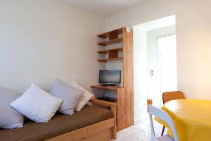 Zimmer mit einem Sofa mit Kissen und einem TV in der Unterkunft Maison près de la plage in Sète