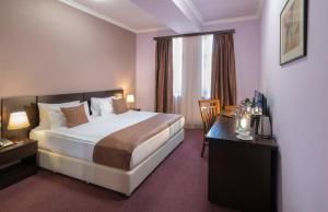 ein Hotelzimmer mit Bett und Schreibtisch in der Unterkunft Ani Central Inn in Yerevan