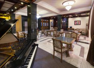 ein Zimmer mit Klavier, Tischen und Stühlen in der Unterkunft Ani Central Inn in Yerevan
