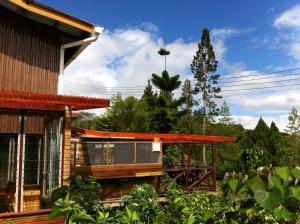 a house with a deck and trees in the background at Mile 36 Lodge in Kundasang