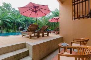 un grupo de sillas con sombrillas y una piscina en Khaolak Mohin Tara Resort - SHA Certified en Khao Lak