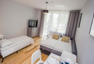 Cette petite chambre comprend un lit, une table et une télévision. dans l'établissement CR Uroczy Apartament w Centrum Nowy Świat 18, à Białystok