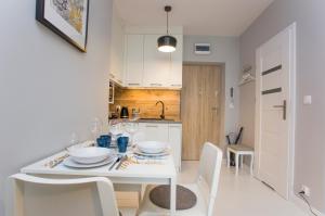 Il comprend une cuisine et une salle à manger avec une table et des chaises blanches. dans l'établissement CR Uroczy Apartament w Centrum Nowy Świat 18, à Białystok