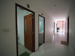 a hallway with a wooden door and a bathroom at WEE HOSTEL in Kanchanaburi