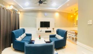 a living room with two blue chairs and a tv at Homestay Cahaya 2 Seri Iskandar in Seri Iskandar
